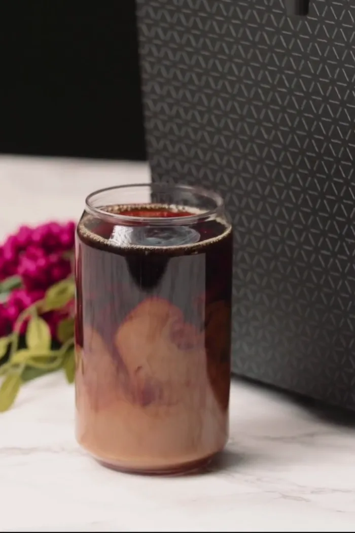 Cold brew layered with cream in a can glass, beside a DRNX machine