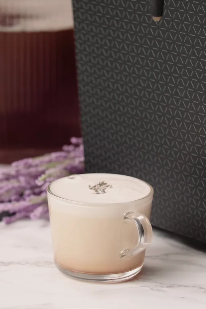 A London Fog in a glass mug beside a DRNX machine, dried lavender and loose tea on slate